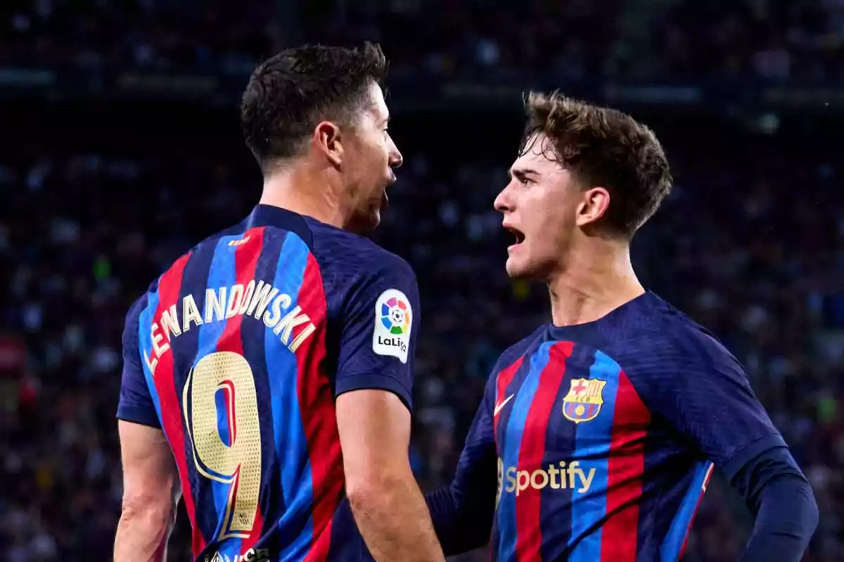 Two FC Barcelona soccer players on the field during a match, one of them wearing the number 9 on his jersey.