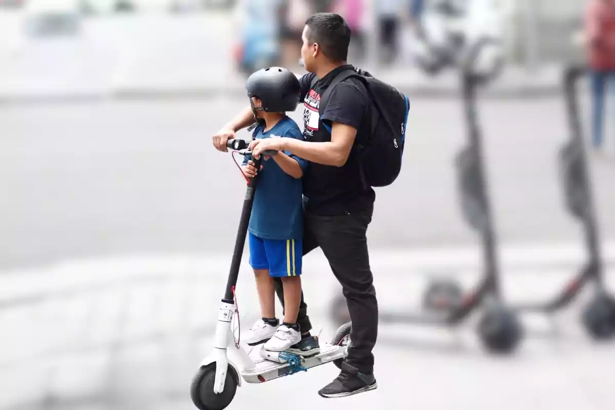 Un adulto y un niño usando un scooter eléctrico en la calle.