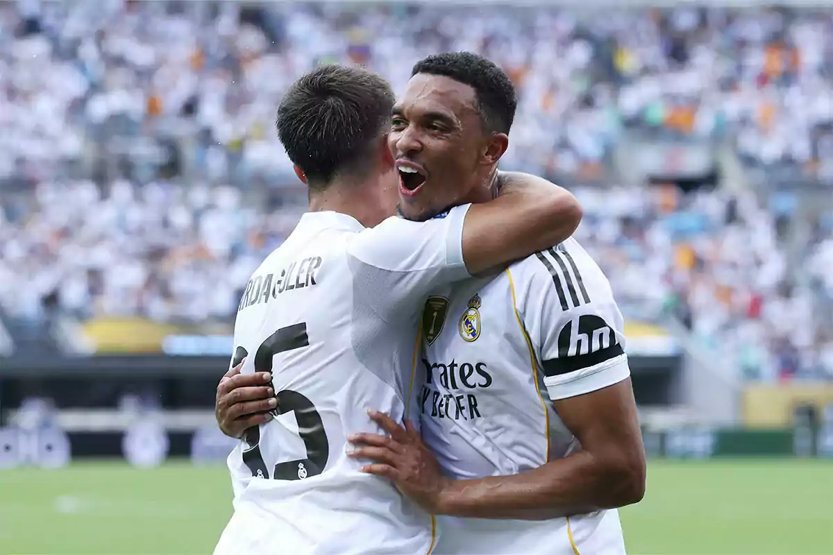 Dos jugadores del Real Madrid celebran un gol abrazándose en el campo frente a una multitud en el estadio Dos jugadores del Real Madrid celebran un gol abrazándose en el campo frente a una multitud en el estadio
