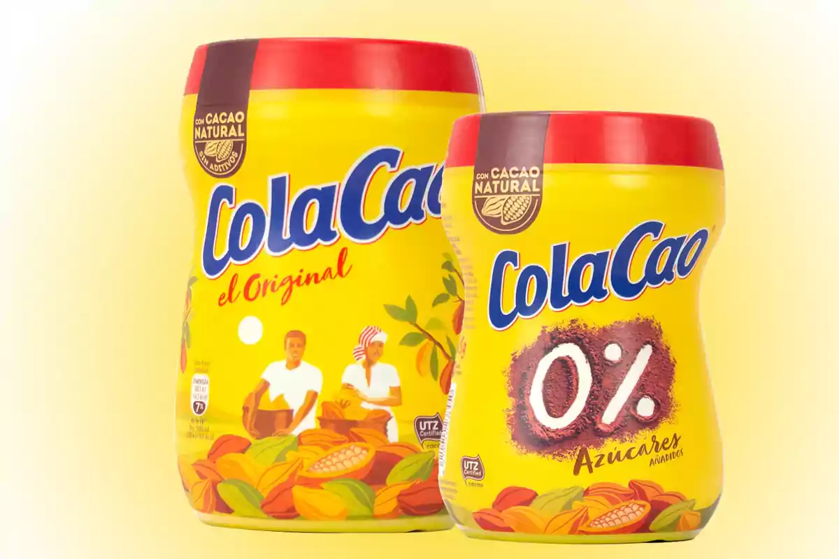 Dos envases de ColaCao en fondo amarillo, uno es el original y el otro es la versión sin azúcares añadidos Dos envases de ColaCao en fondo amarillo, uno es el original y el otro es la versión sin azúcares añadidos
