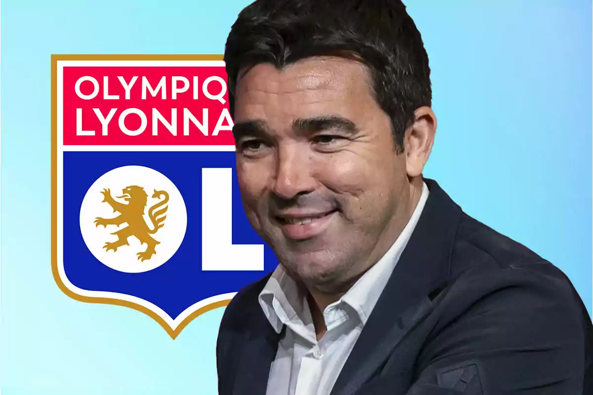 Hombre sonriente con saco oscuro frente al escudo del Olympique de Lyon sobre fondo azul