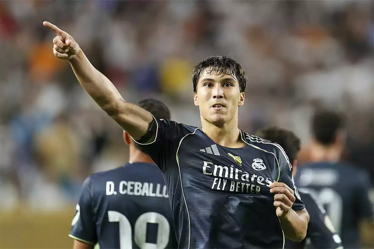 Futbolista del Real Madrid celebrando un gol mientras señala con el brazo extendido y sostiene la camiseta del equipo Futbolista del Real Madrid celebrando un gol mientras señala con el brazo extendido y sostiene la camiseta del equipo
