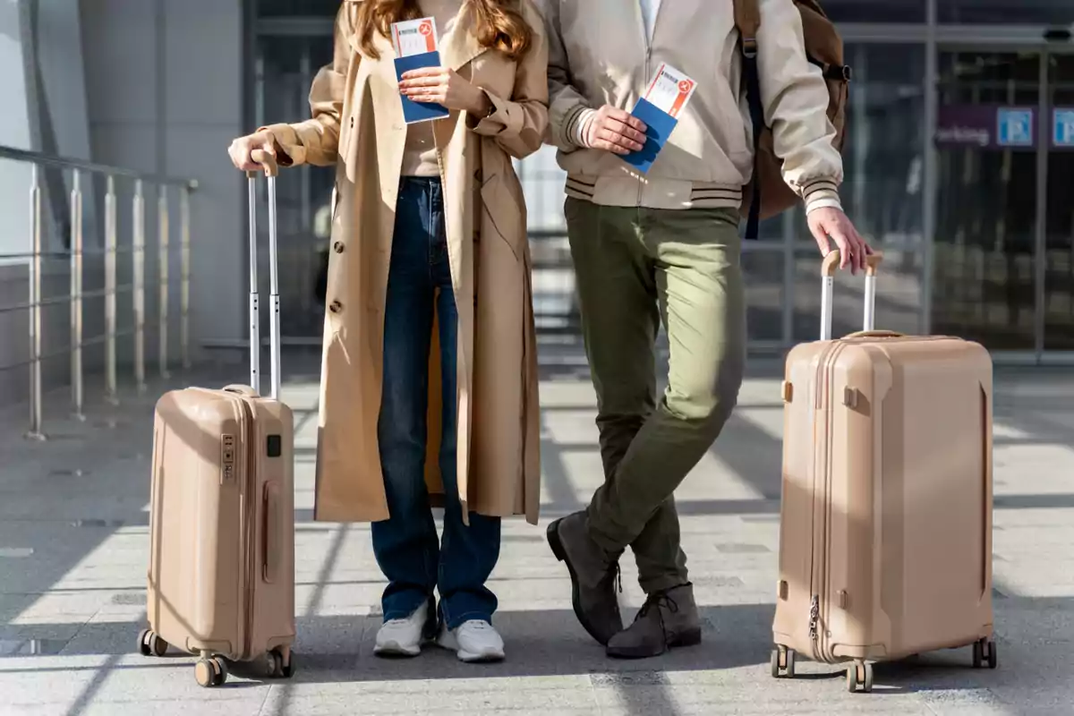 Pareja de viajeros con maletas y boletos de avión en la mano en un aeropuerto Pareja de viajeros con maletas y boletos de avión en la mano en un aeropuerto