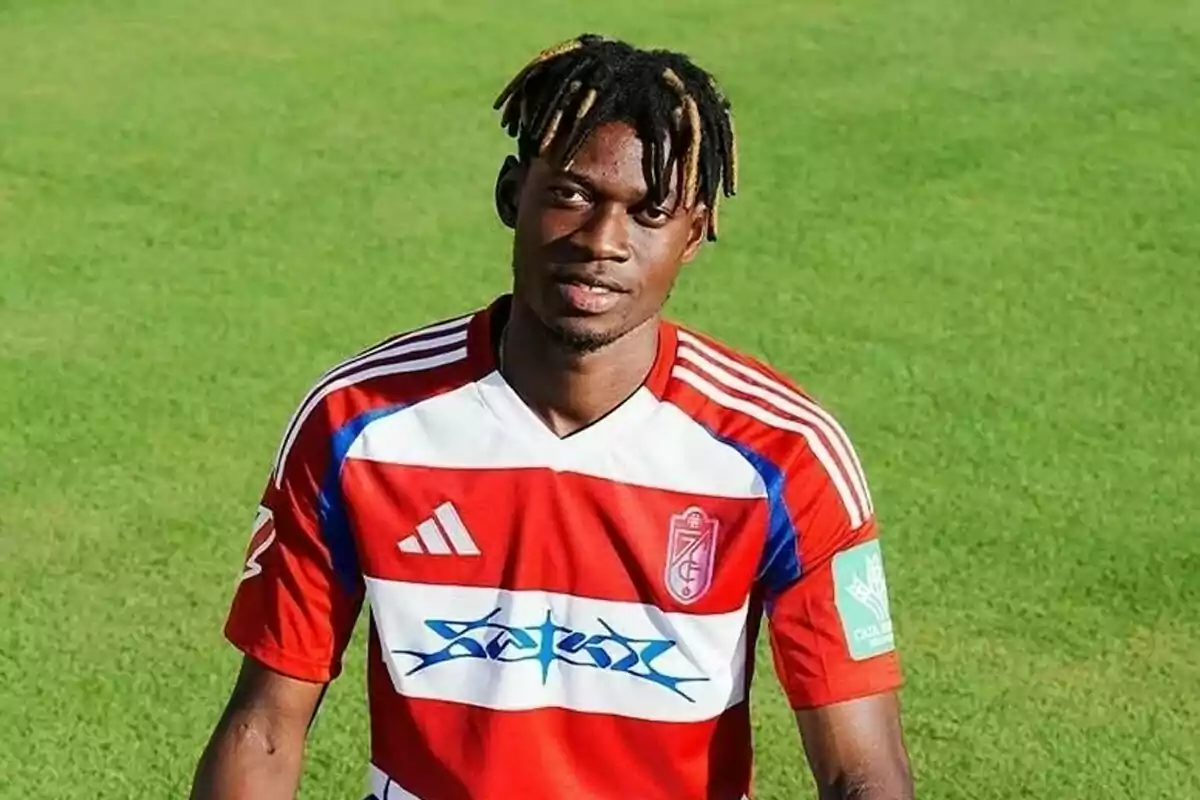 Soccer player wearing a red and white jersey posing on a grass field Soccer player wearing a red and white jersey posing on a grass field