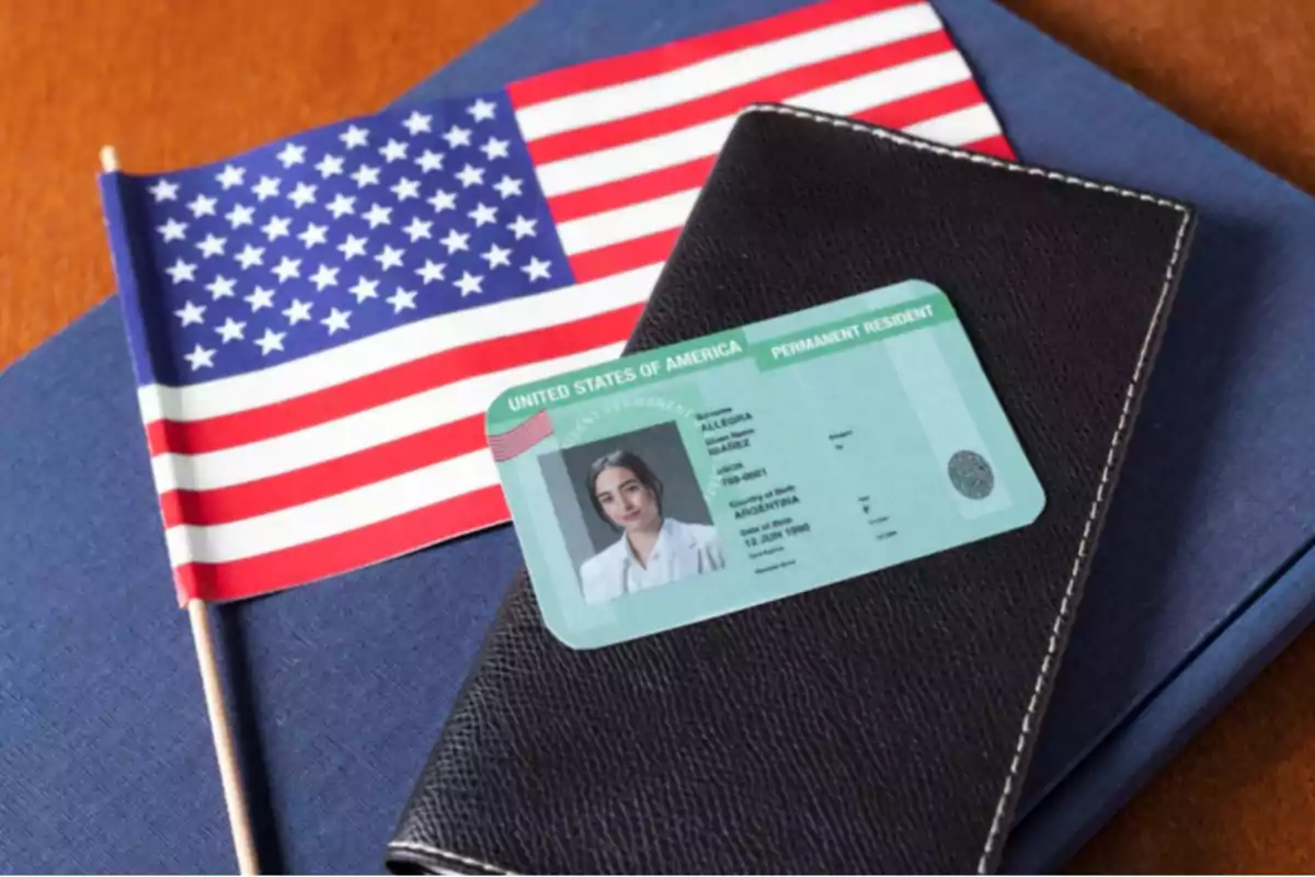 Tarjeta de residencia permanente de Estados Unidos sobre una cartera negra junto a una bandera estadounidense Tarjeta de residencia permanente de Estados Unidos sobre una cartera negra junto a una bandera estadounidense