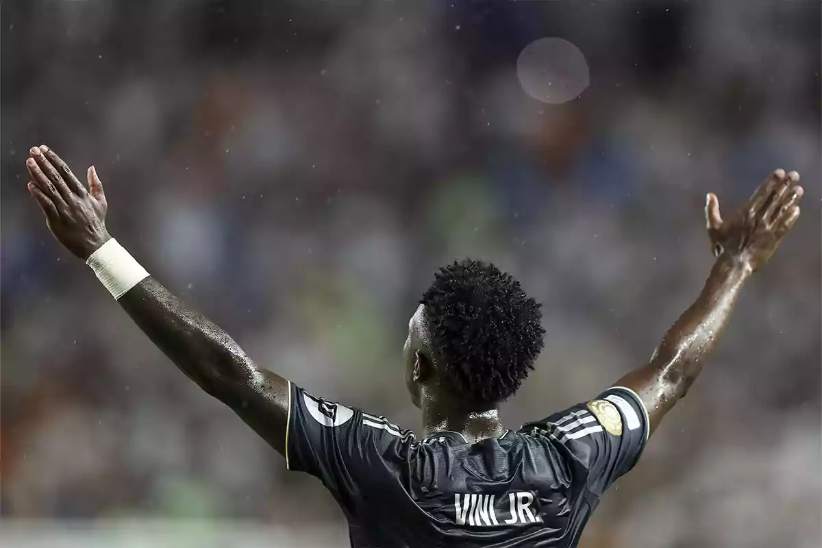 Futbolista de espaldas con los brazos extendidos celebrando bajo la lluvia en un estadio Futbolista de espaldas con los brazos extendidos celebrando bajo la lluvia en un estadio