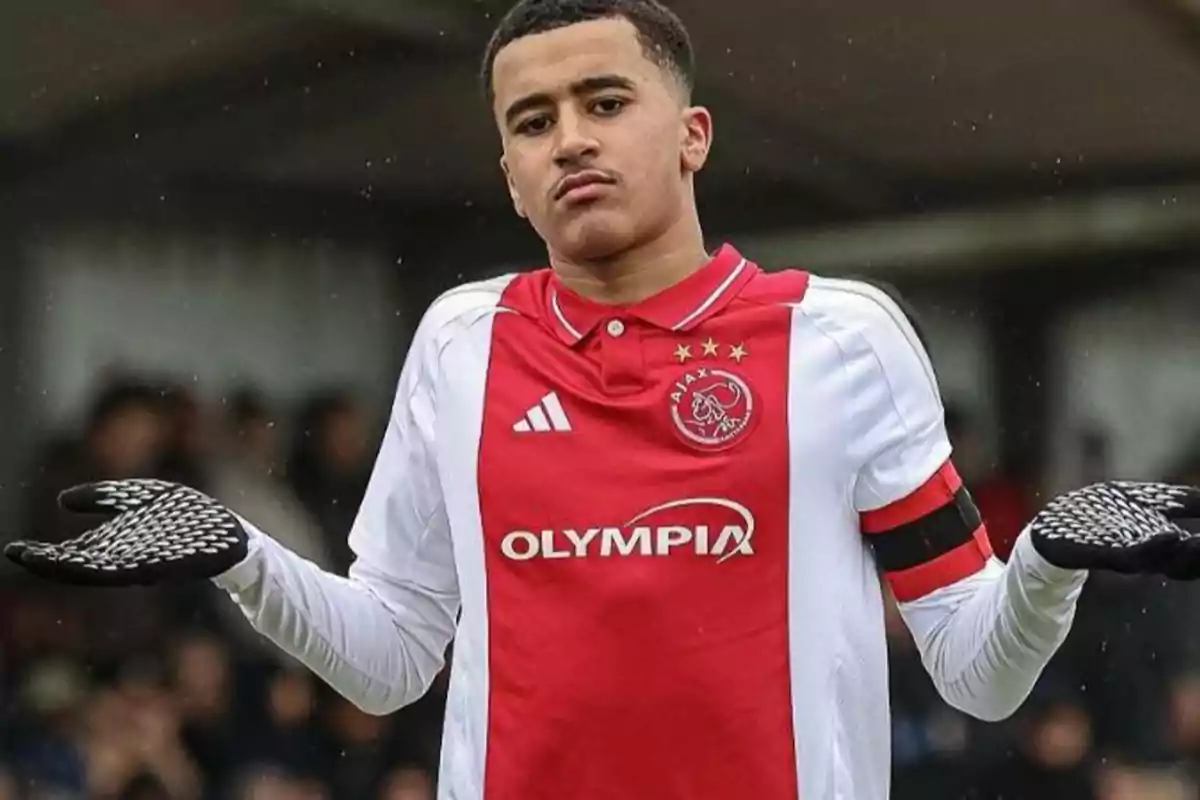 Soccer player in an Ajax uniform shrugging his shoulders and raising his hands in a gesture of doubt or indifference during a match Soccer player in an Ajax uniform shrugging his shoulders and raising his hands in a gesture of doubt or indifference during a match