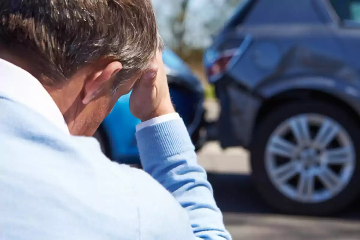 Hombre preocupado sostiene su cabeza mientras observa un accidente de autos Hombre preocupado sostiene su cabeza mientras observa un accidente de autos