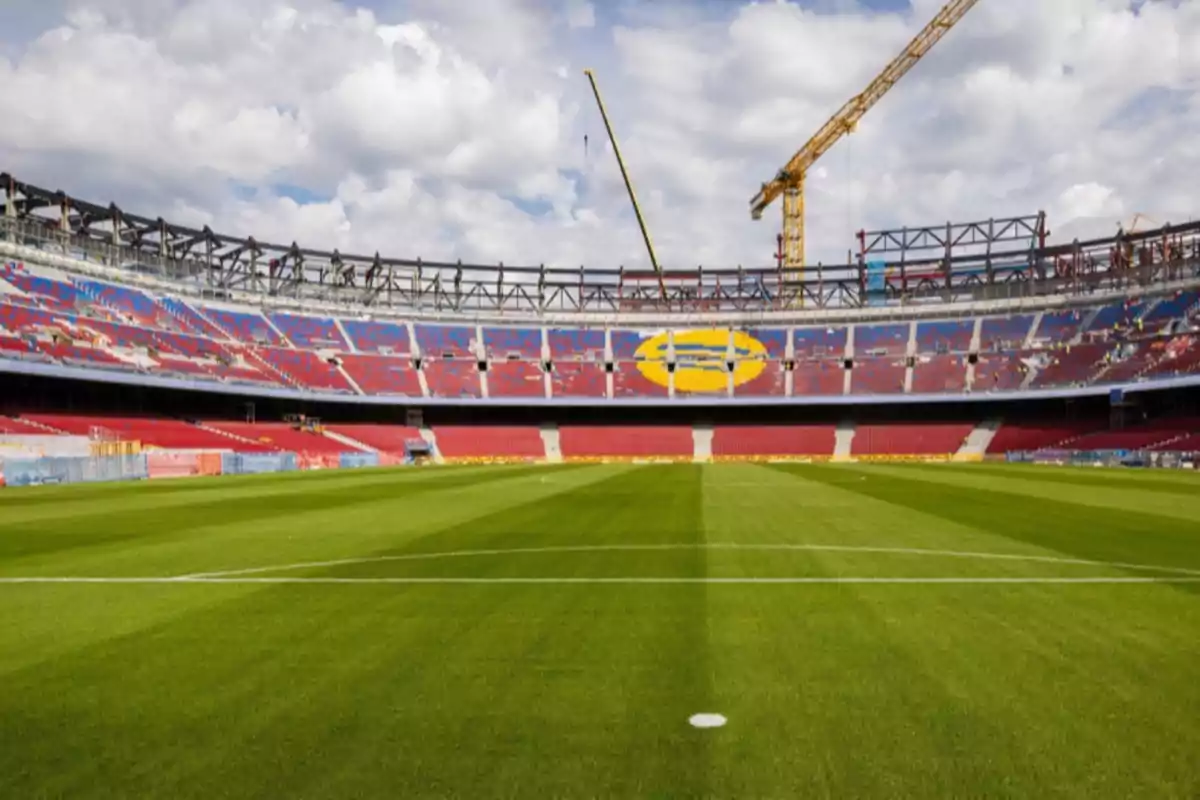 Soccer stadium with empty stands and a crane working on the structure under a cloudy sky