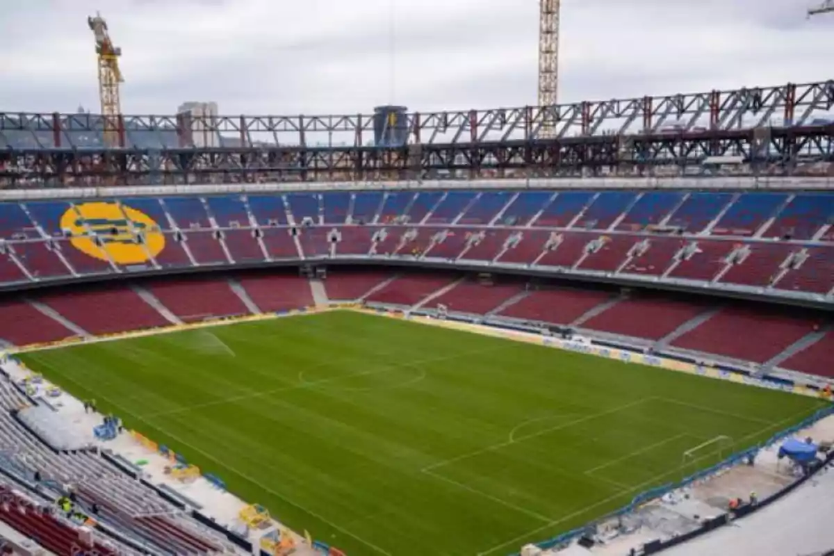 Large soccer stadium with empty stands and construction cranes in the background Large soccer stadium with empty stands and construction cranes in the background