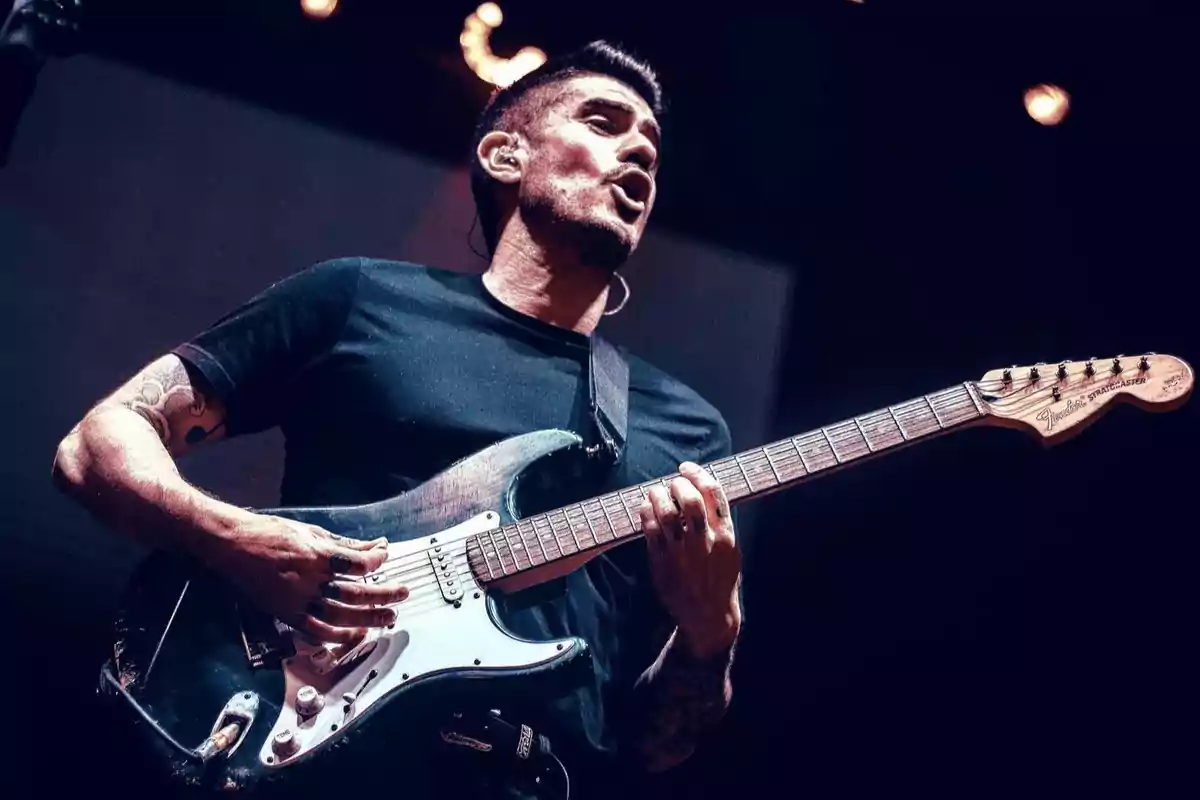 Man playing an electric guitar on stage during a concert Man playing an electric guitar on stage during a concert