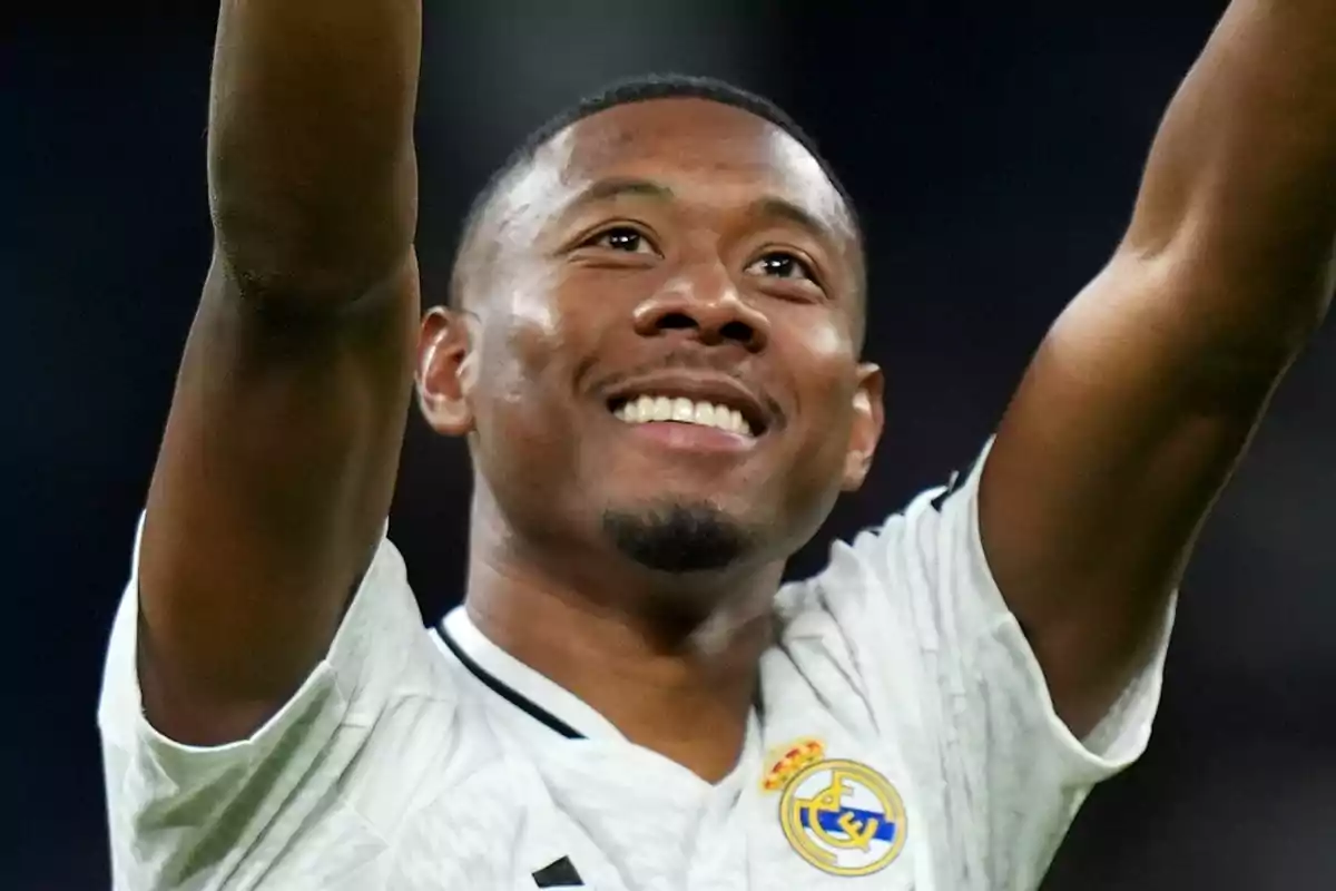 Futbolista con uniforme blanco del Real Madrid sonríe y levanta los brazos celebrando en un estadio
