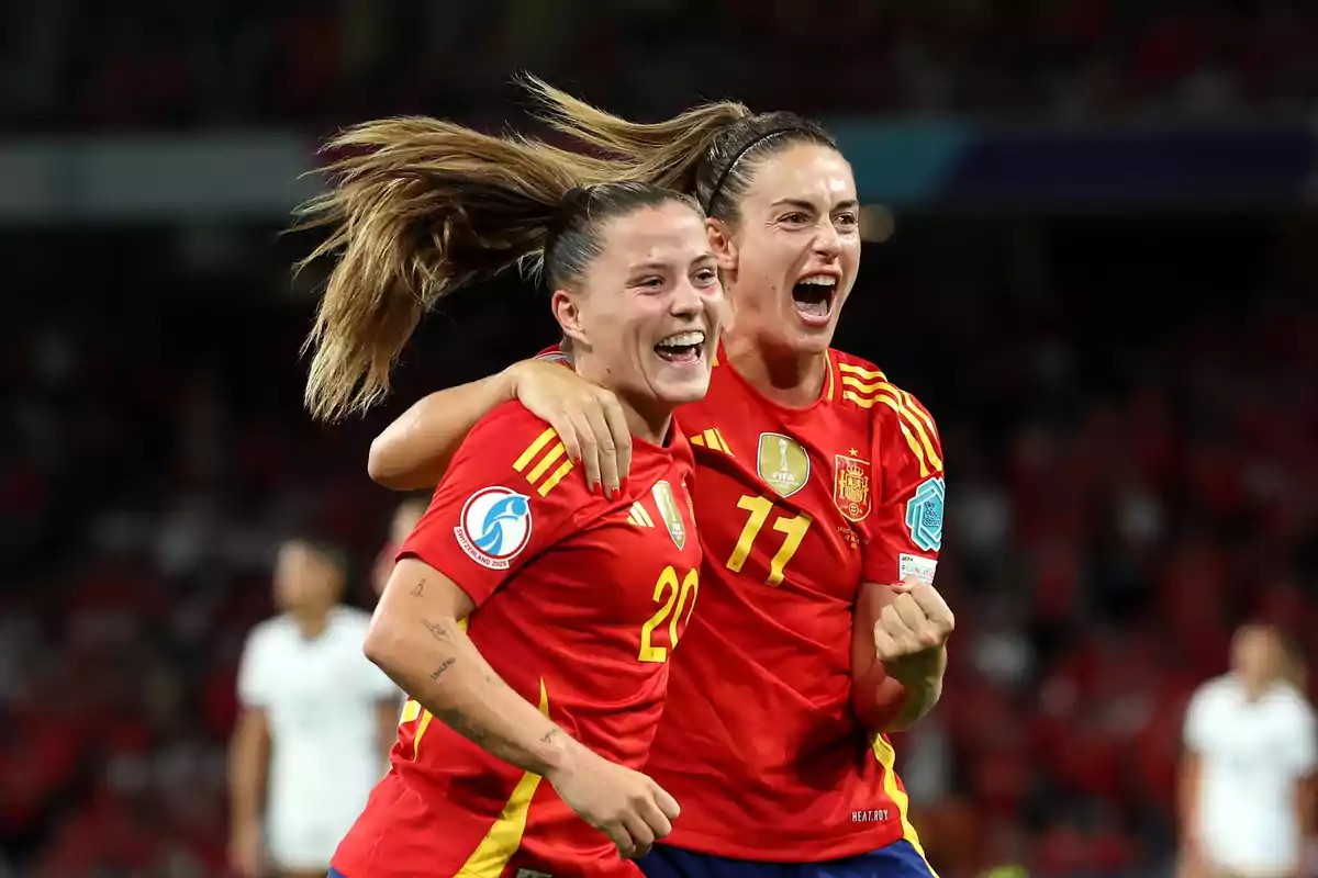 Dos jugadoras de la selección femenina de fútbol de España celebran un gol abrazándose y sonriendo en el campo durante un partido Dos jugadoras de la selección femenina de fútbol de España celebran un gol abrazándose y sonriendo en el campo durante un partido