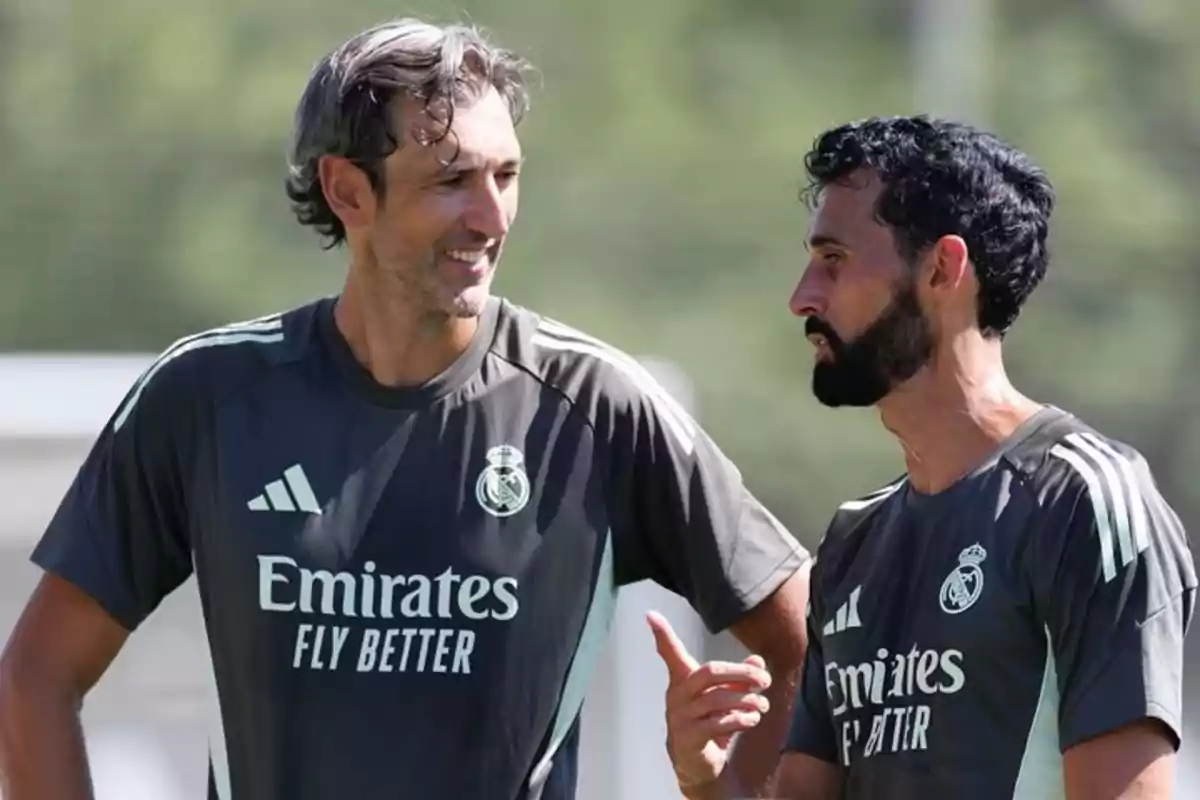 Dos entrenadores del Real Madrid conversan durante un entrenamiento al aire libre, ambos llevan camisetas deportivas del equipo Dos entrenadores del Real Madrid conversan durante un entrenamiento al aire libre, ambos llevan camisetas deportivas del equipo