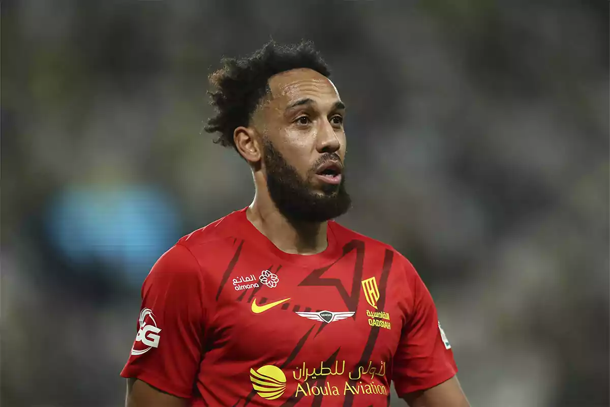 Futbolista con barba y cabello rizado usando un uniforme rojo durante un partido Futbolista con barba y cabello rizado usando un uniforme rojo durante un partido