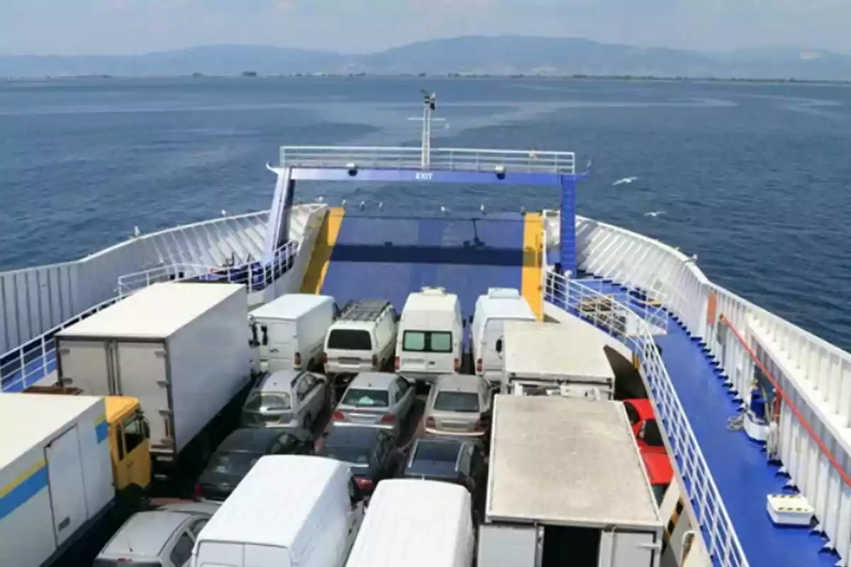Varios autos y camiones transportados en la cubierta de un ferry navegando por el mar