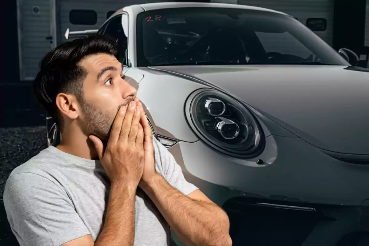 Hombre sorprendido con las manos en la boca frente a un auto deportivo gris