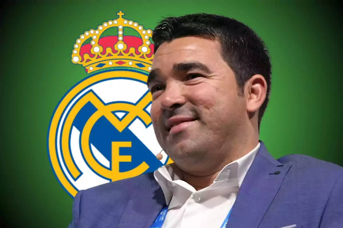 Hombre con saco azul sonriendo frente al escudo del Real Madrid sobre fondo verde