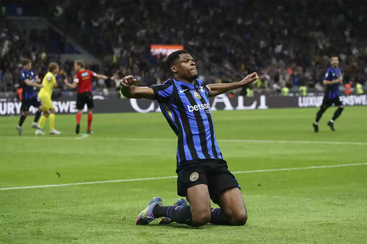 Futbolista del Inter de Milán celebrando un gol de rodillas en el campo con los brazos extendidos y el estadio lleno de aficionados al fondo Futbolista del Inter de Milán celebrando un gol de rodillas en el campo con los brazos extendidos y el estadio lleno de aficionados al fondo