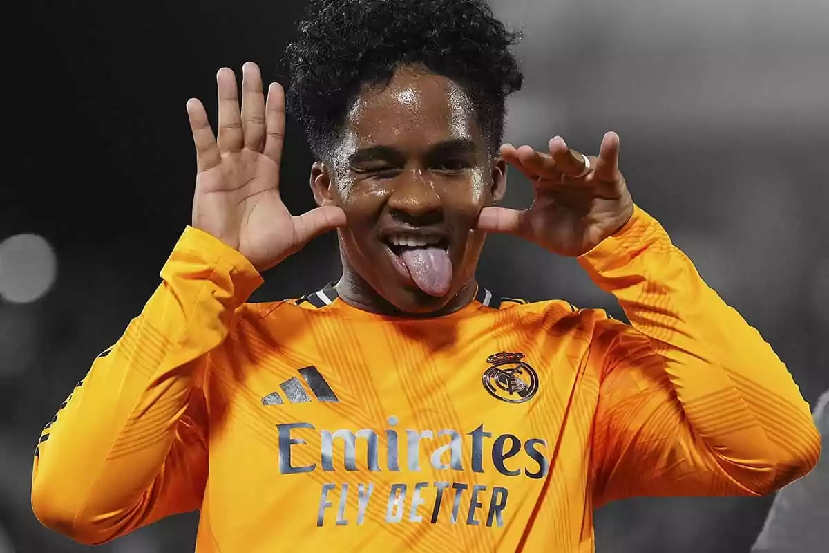 Futbolista con uniforme naranja del Real Madrid celebrando con un gesto divertido sacando la lengua y guiñando un ojo