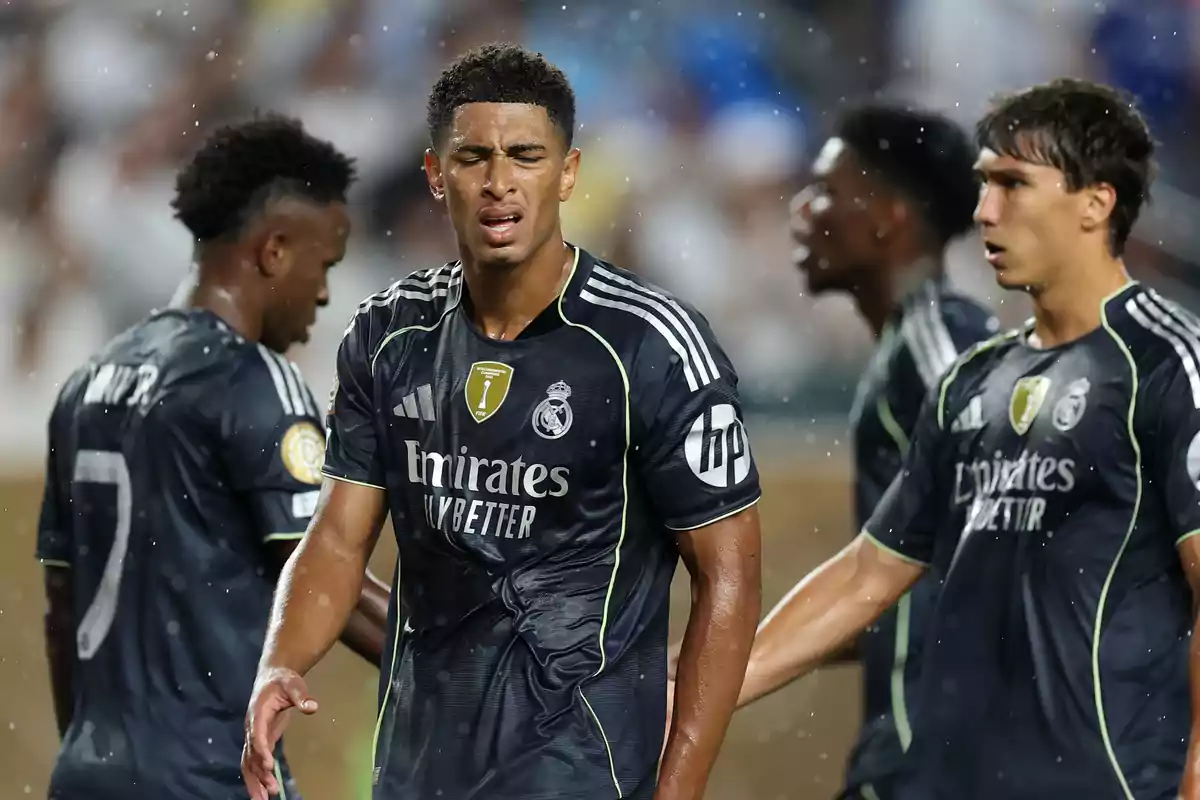Real Madrid players in dark uniforms during a match in the rain, showing expressions of effort and concentration