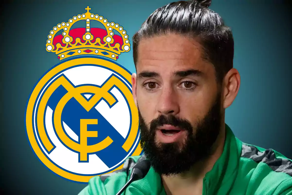 Hombre con barba y cabello recogido hablando frente a un micrófono con el escudo del Real Madrid de fondo