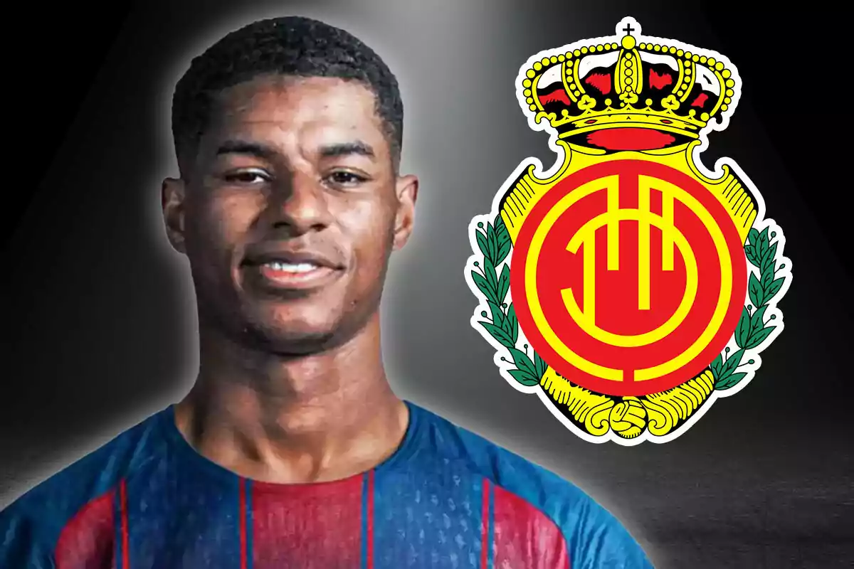 Un futbolista con camiseta azul y roja junto al escudo del Real Mallorca