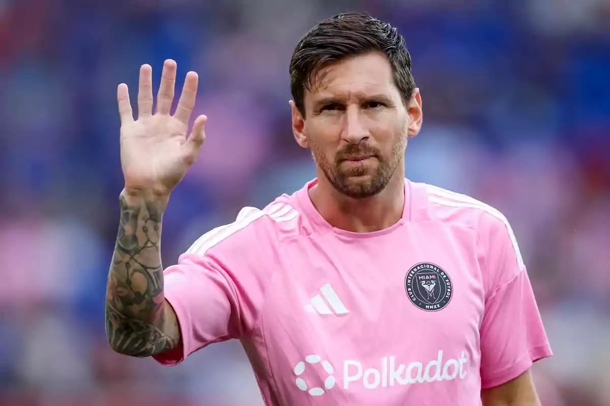 Futbolista con camiseta rosa del Inter Miami levantando la mano en señal de saludo