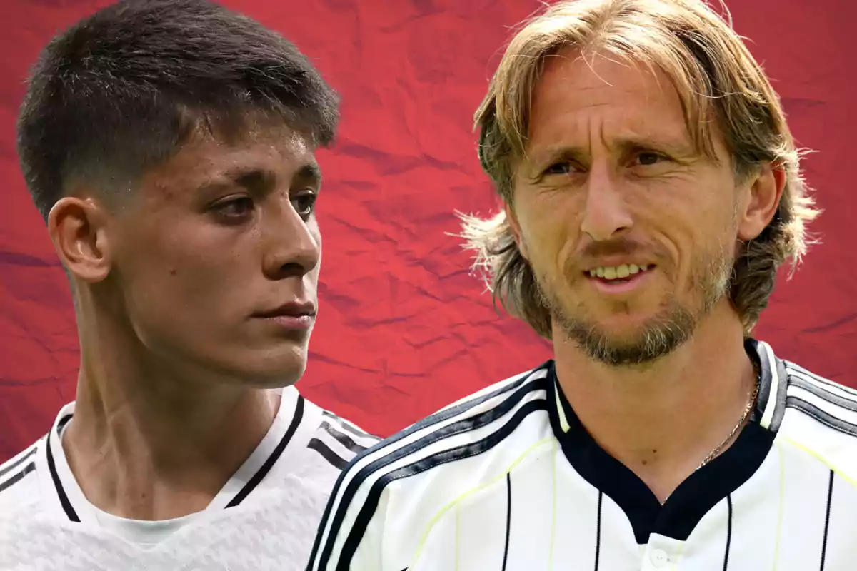Dos futbolistas con uniforme blanco y negro posan frente a un fondo rojo