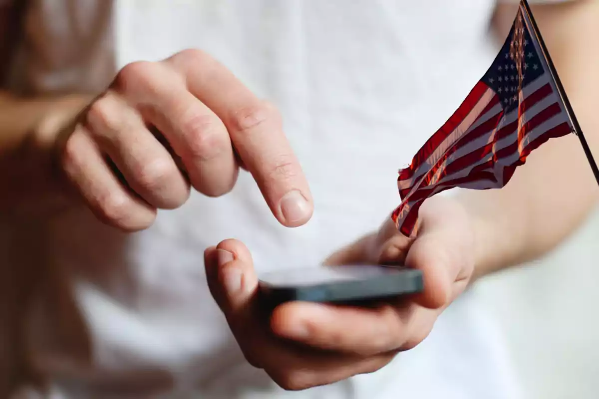 Person using a mobile phone with a small United States flag in their hand