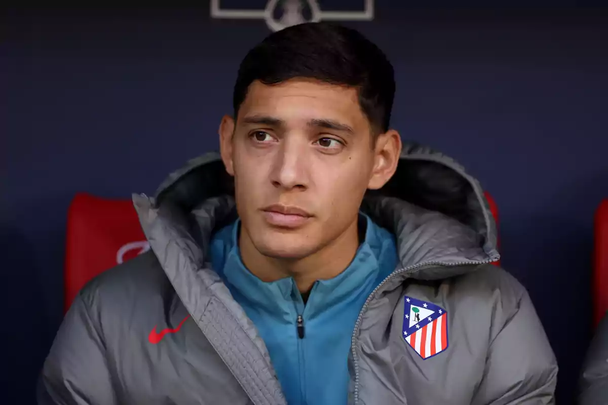 Jugador de fútbol con chaqueta gris del Atlético de Madrid sentado en el banquillo mirando hacia un lado Jugador de fútbol con chaqueta gris del Atlético de Madrid sentado en el banquillo mirando hacia un lado