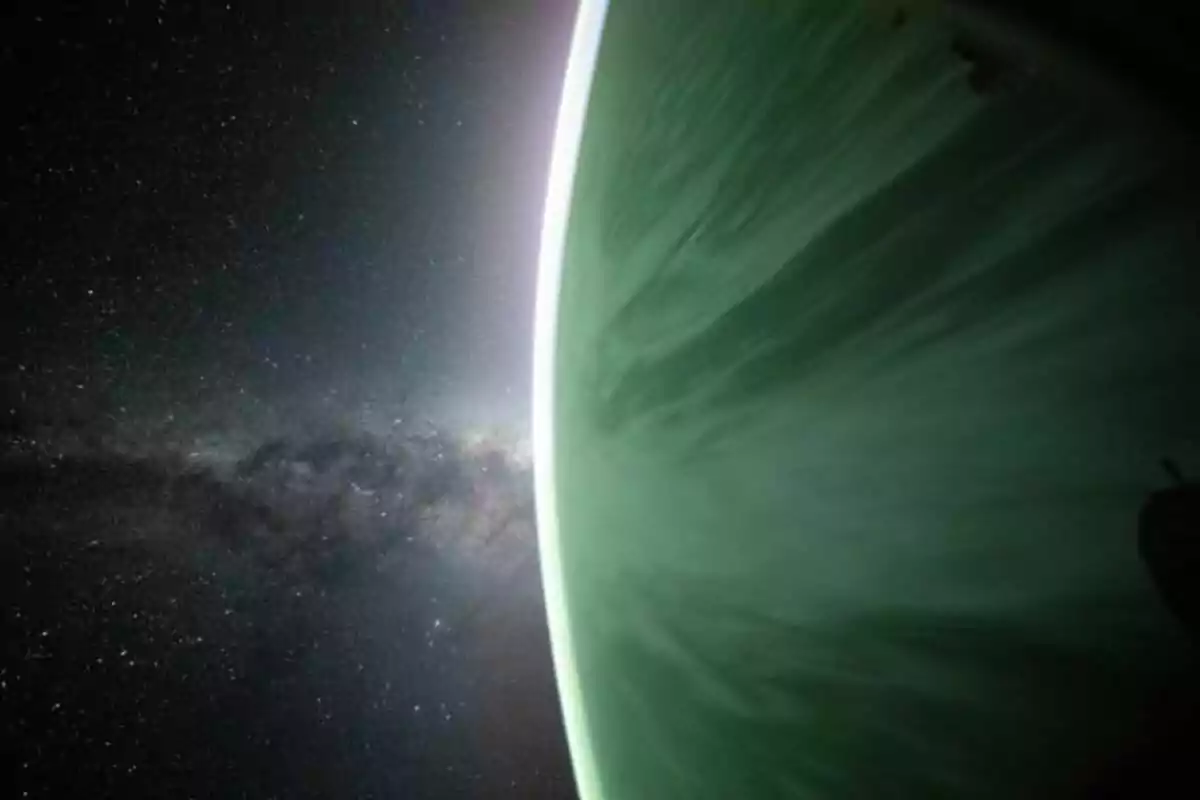 Vista de un planeta verde con su atmósfera iluminada y el espacio estrellado de fondo Vista de un planeta verde con su atmósfera iluminada y el espacio estrellado de fondo