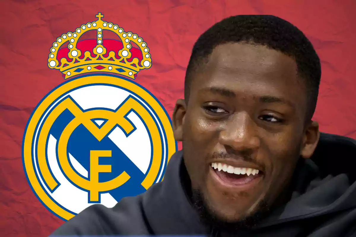 Hombre sonriendo con el escudo del Real Madrid de fondo sobre una pared roja