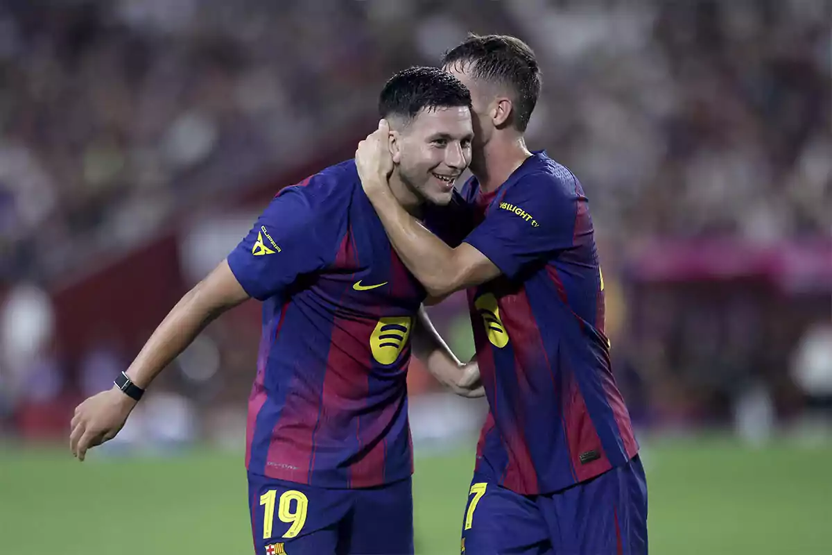 Dos futbolistas del FC Barcelona celebran un gol abrazándose en el campo durante un partido Dos futbolistas del FC Barcelona celebran un gol abrazándose en el campo durante un partido