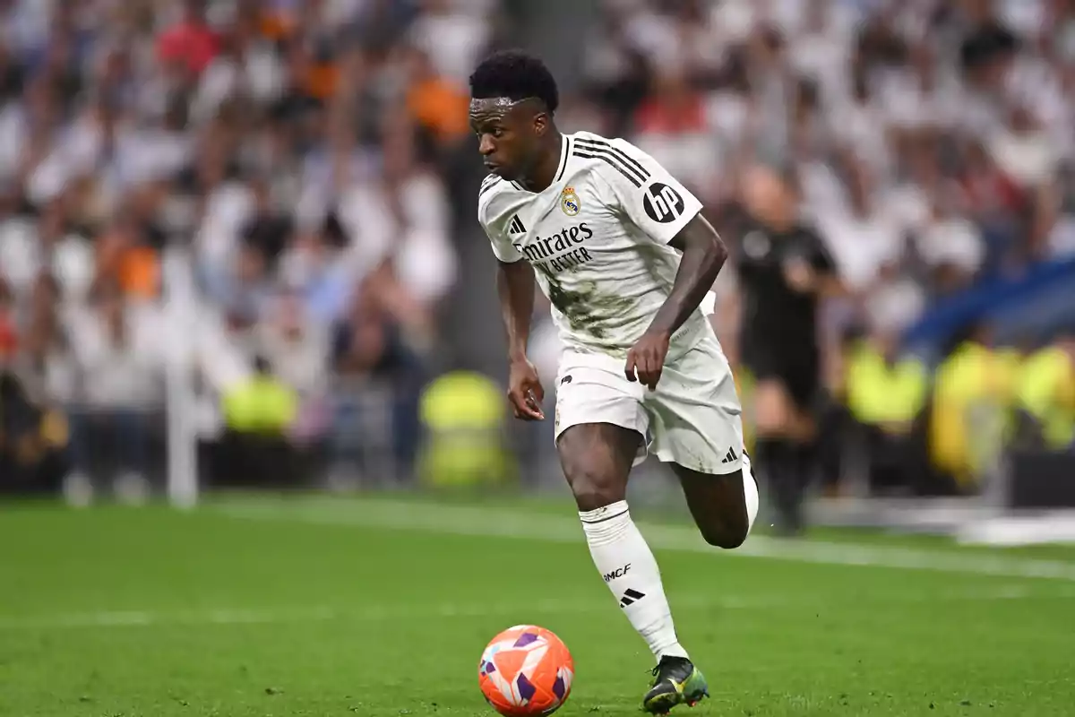 Futbolista del Real Madrid corriendo con el balón durante un partido en un estadio lleno de aficionados Futbolista del Real Madrid corriendo con el balón durante un partido en un estadio lleno de aficionados