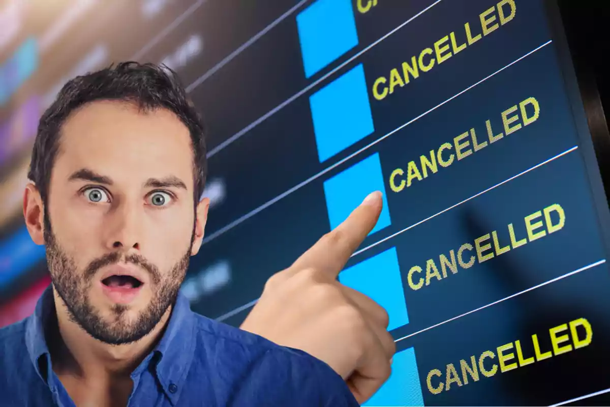Hombre sorprendido señalando una pantalla de vuelos cancelados en un aeropuerto