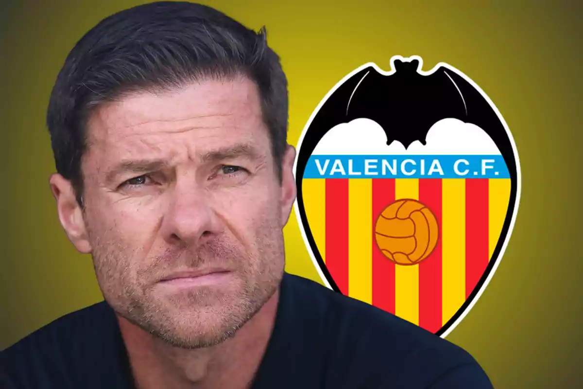 A man with short hair and a beard looking forward with the Valencia CF crest in the background on a yellow backdrop.
