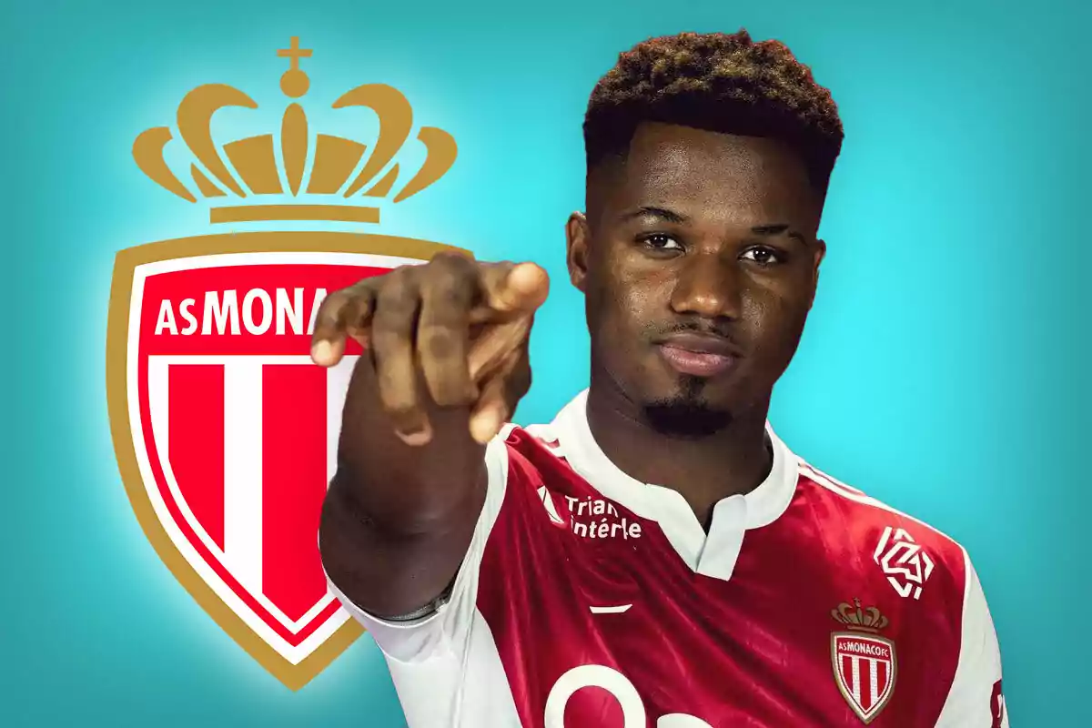 Futbolista con el uniforme del AS Monaco señalando hacia el frente con el escudo del club de fondo y fondo azul