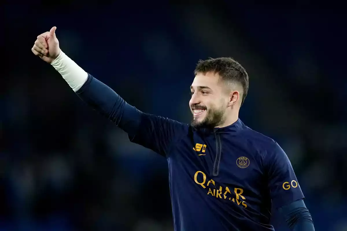 Soccer player in a blue PSG uniform smiles and gives a thumbs up in approval