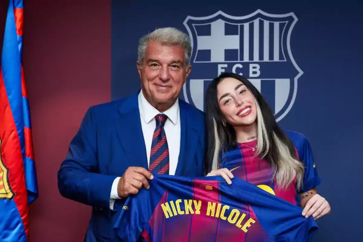 Two people smile while holding an FC Barcelona jersey with the name Nicky Nicole in front of the club’s crest. Two people smile while holding an FC Barcelona jersey with the name Nicky Nicole in front of the club’s crest.