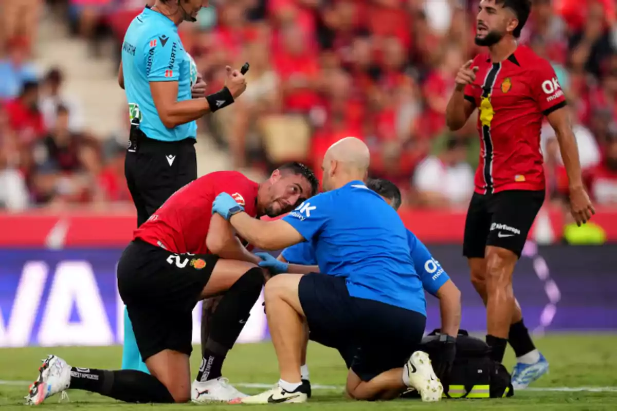A player receives medical attention on the field while a referee and another player watch during a match. A player receives medical attention on the field while a referee and another player watch during a match.