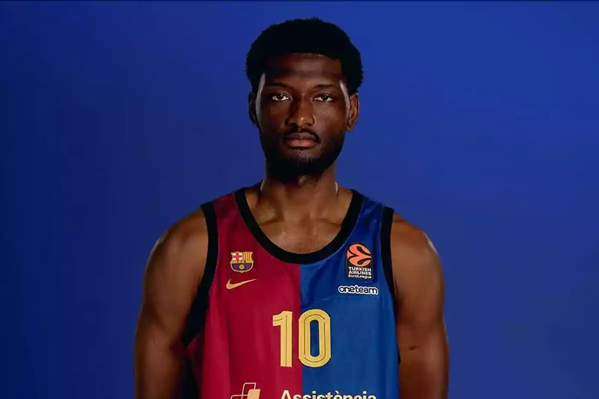 Jugador de baloncesto con uniforme del FC Barcelona posando frente a un fondo azul Jugador de baloncesto con uniforme del FC Barcelona posando frente a un fondo azul