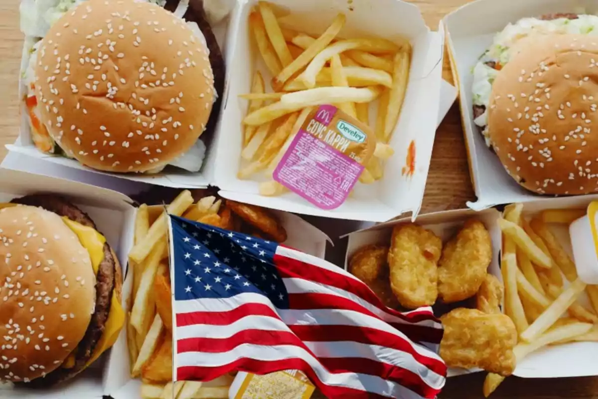 Comida rápida con hamburguesas, papas fritas, nuggets de pollo y una bandera de Estados Unidos en primer plano