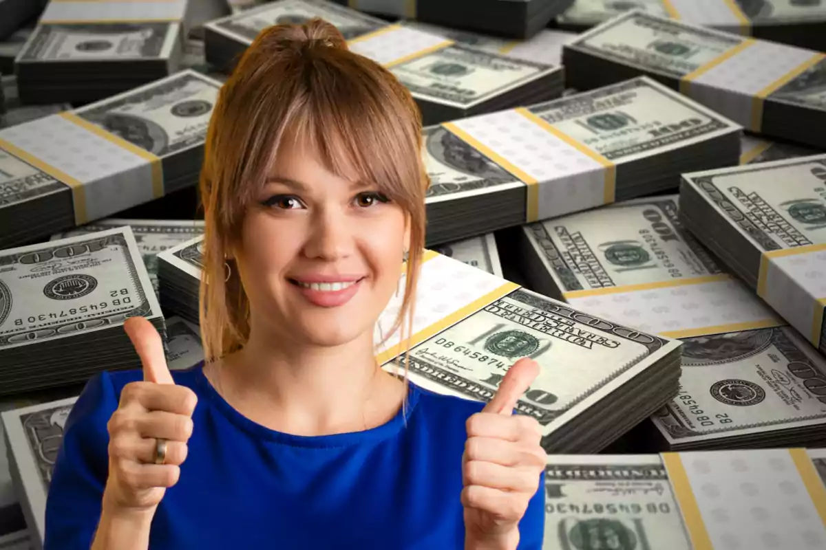 Mujer sonriente con pulgares arriba frente a muchos fajos de billetes de cien dólares