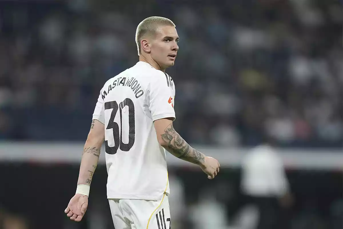 Futbolista con el cabello corto y tatuajes en los brazos usando un uniforme blanco con el número 30 y el nombre Mastantuono en la espalda durante un partido Futbolista con el cabello corto y tatuajes en los brazos usando un uniforme blanco con el número 30 y el nombre Mastantuono en la espalda durante un partido