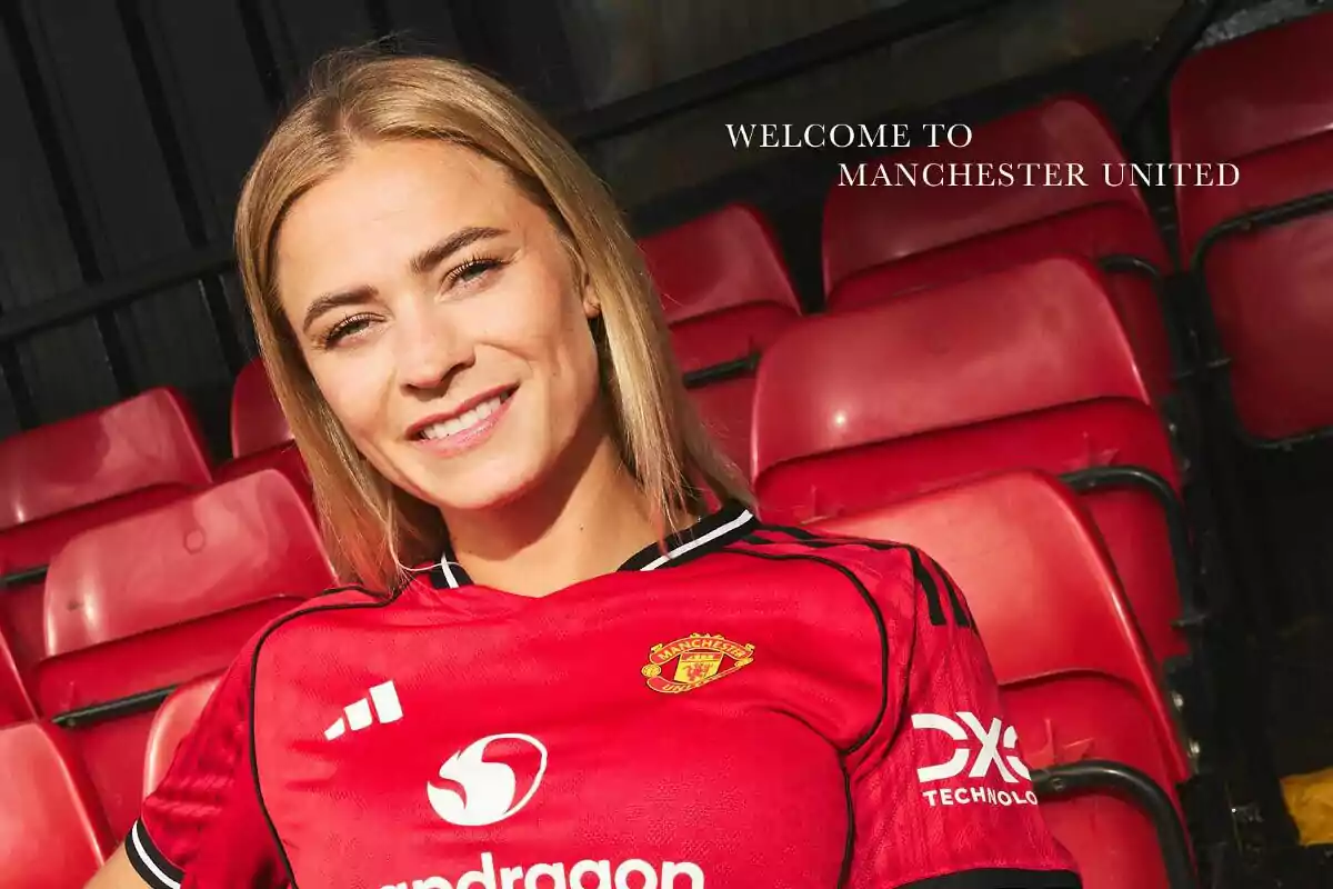 Futbolista sonriente con camiseta del Manchester United posando en las gradas del estadio Futbolista sonriente con camiseta del Manchester United posando en las gradas del estadio