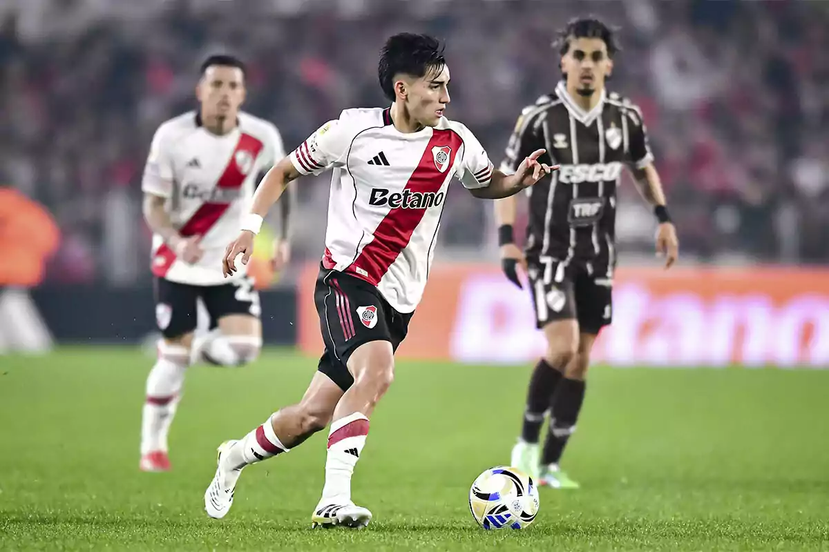 Ian Subiabre conduciendo el balón durante un partido mientras es perseguido por un rival y un compañero. Ian Subiabre conduciendo el balón durante un partido mientras es perseguido por un rival y un compañero.