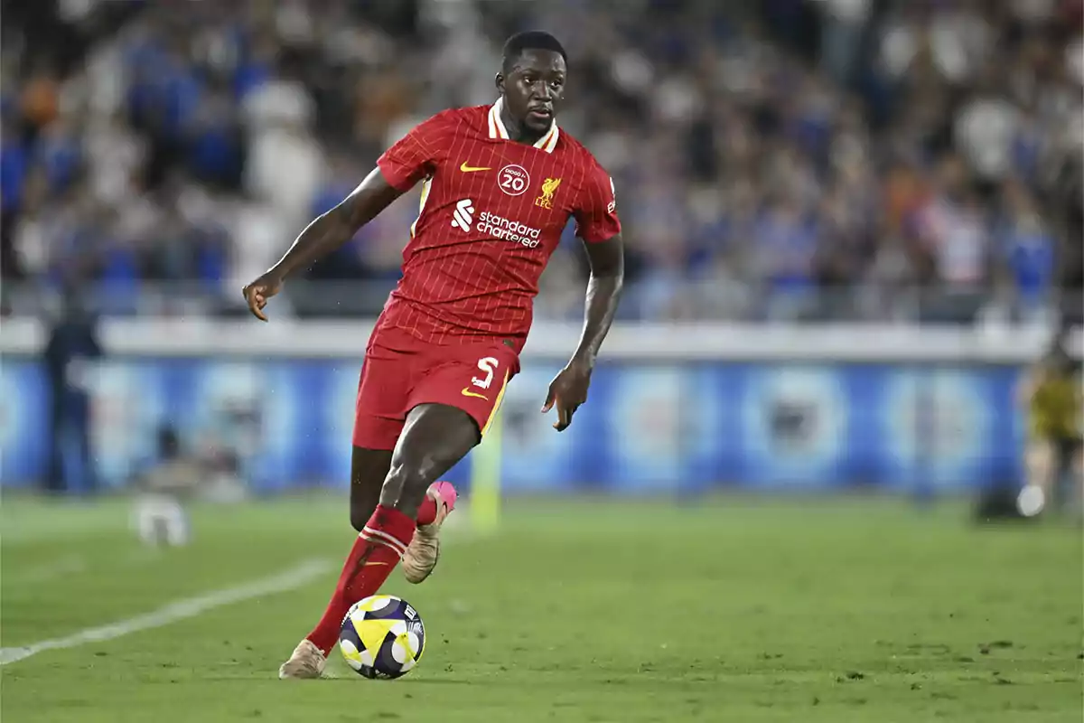 Soccer player in a red uniform controlling the ball during a match on grass with a blurred crowd in the background Soccer player in a red uniform controlling the ball during a match on grass with a blurred crowd in the background