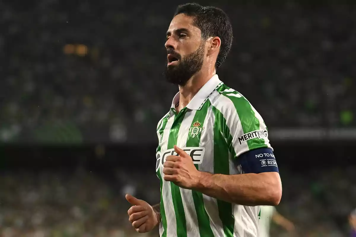 Futbolista con barba y cabello corto usando el uniforme verde y blanco del Real Betis durante un partido Futbolista con barba y cabello corto usando el uniforme verde y blanco del Real Betis durante un partido