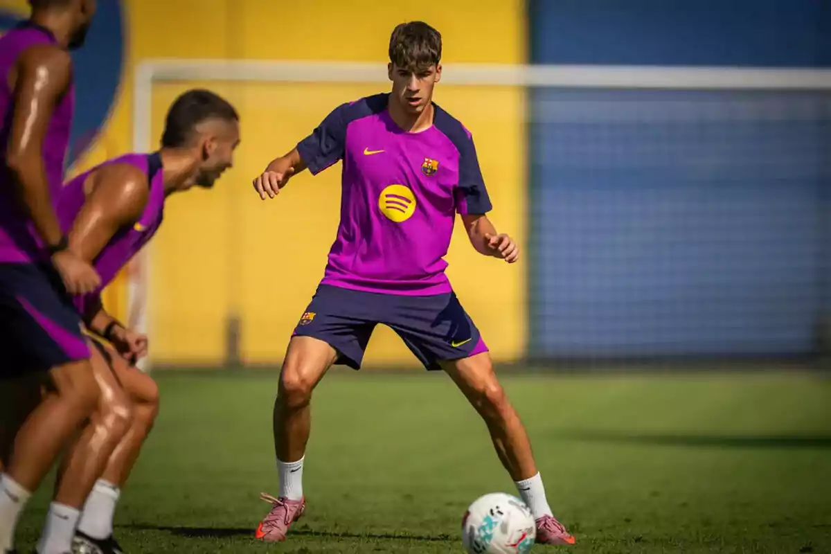 Jugadores de fútbol entrenando en un campo con uniforme morado y azul del FC Barcelona Jugadores de fútbol entrenando en un campo con uniforme morado y azul del FC Barcelona
